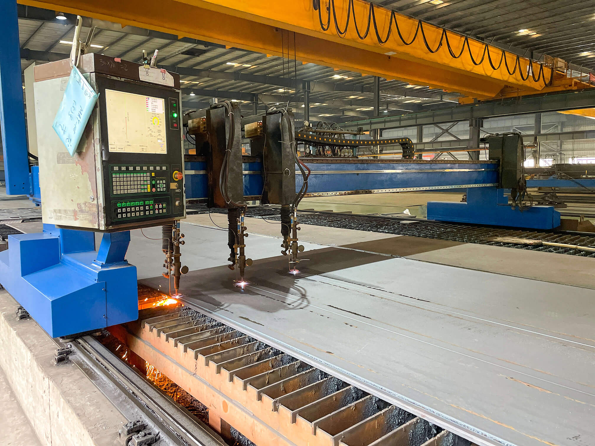 Factory equipment performing plasma cutting on steel.